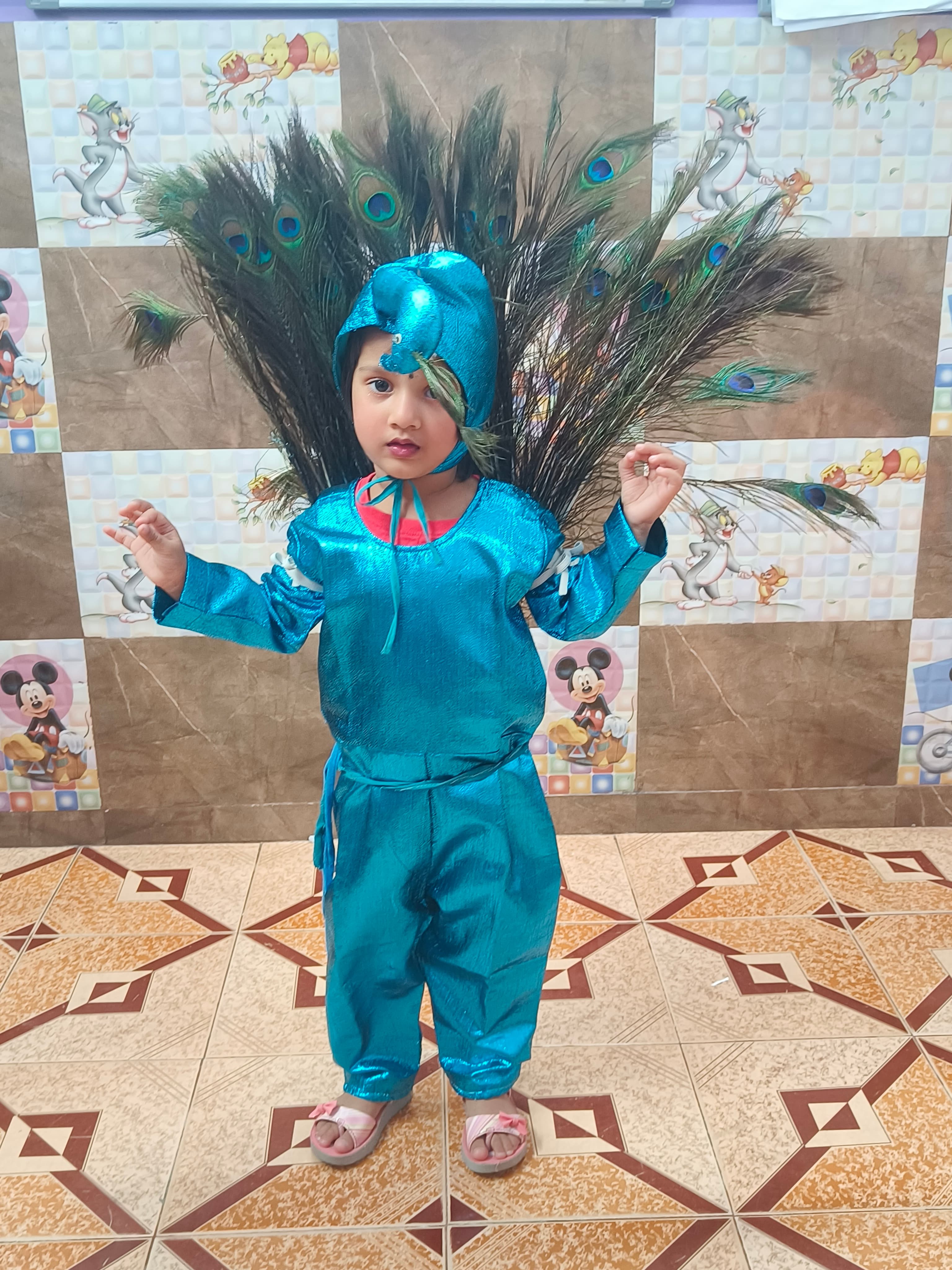 Girl in shiny blue peacock costume with feather tail spread on Animal Day